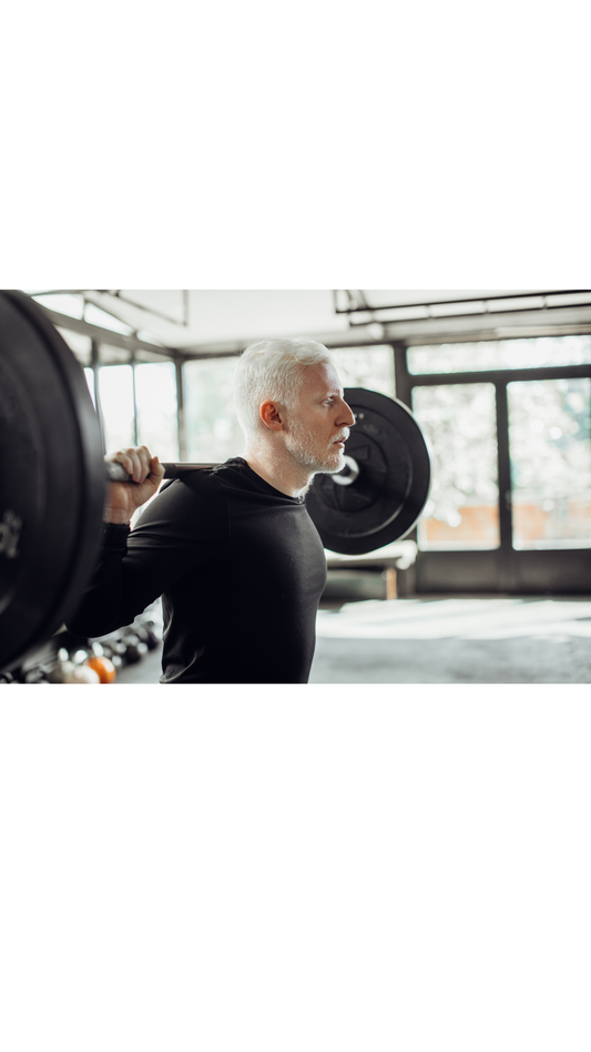 Older male weightlifting in gym, doing squats.
